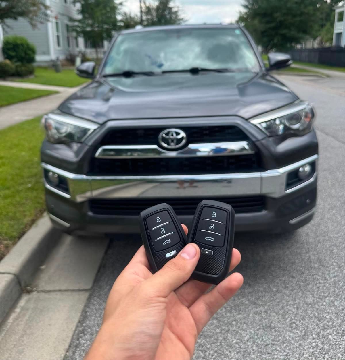 Two newly cut and programmed Toyota smart key fobs held in front of the SUV they were made for